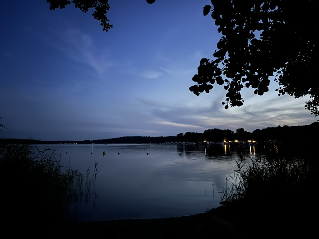 Jabelscher See in der Dämmerung mit beleuchteten Booten am Hafen Damerow