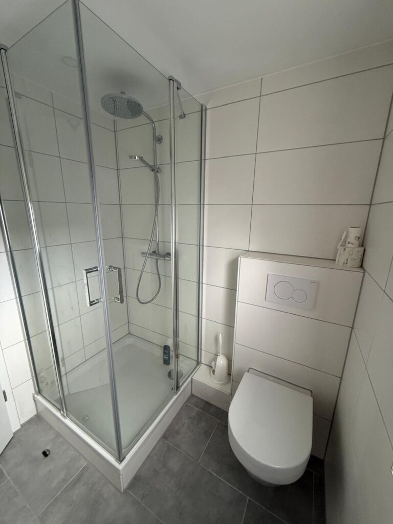 Modernes Badezimmer der Ferienwohnung mit ebenerdiger Dusche und WC