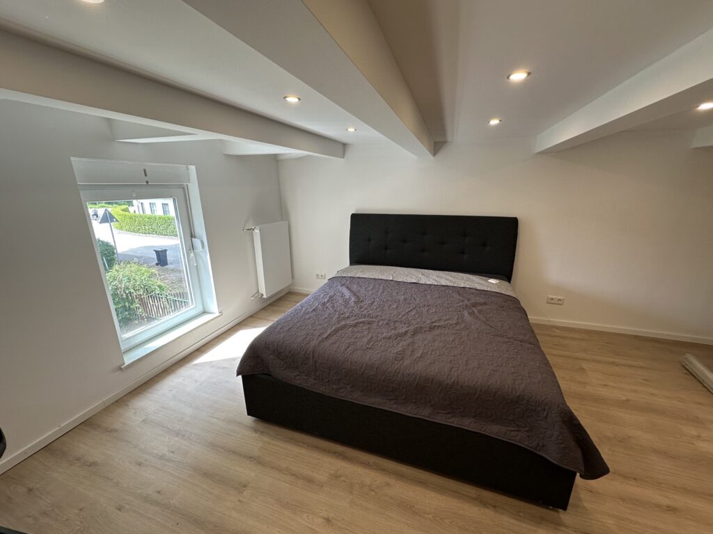 Helles Schlafzimmer der Ferienwohnung mit Doppelbett und Fenster zum Garten