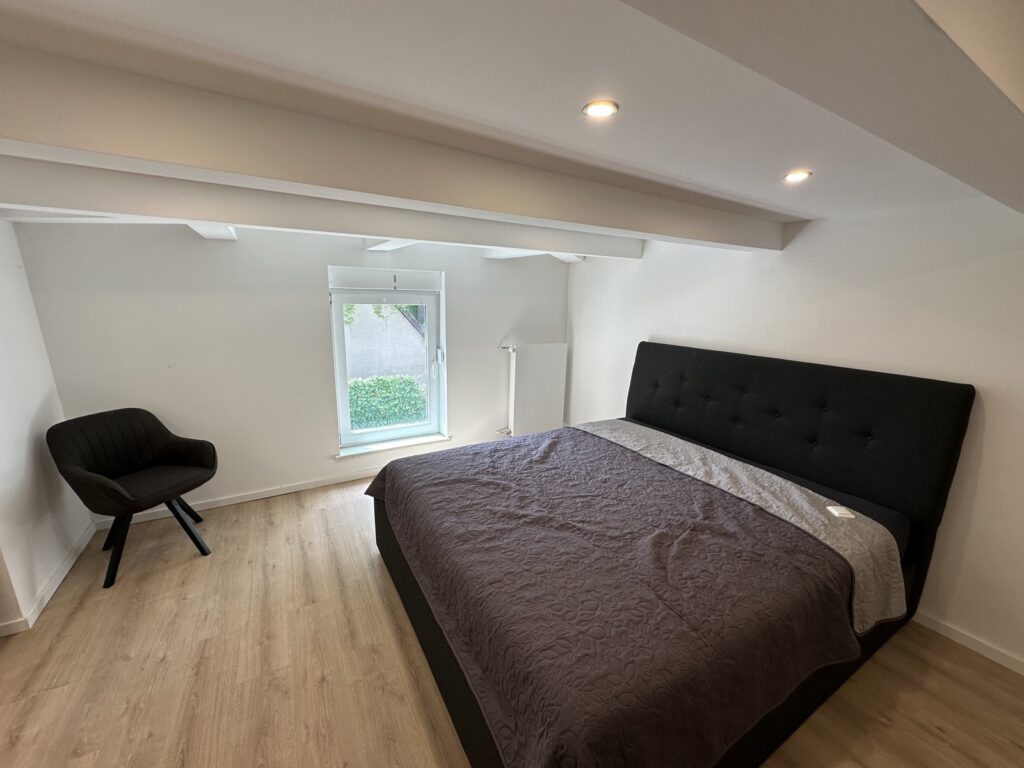 Schlafzimmer mit Doppelbett und gemütlichem Sessel in der Ferienwohnung Damerow